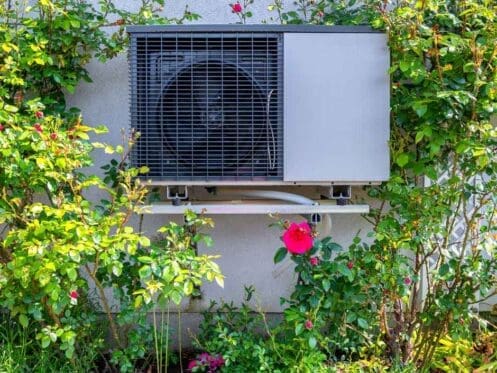 Heat pump on a small ledge outside of a home